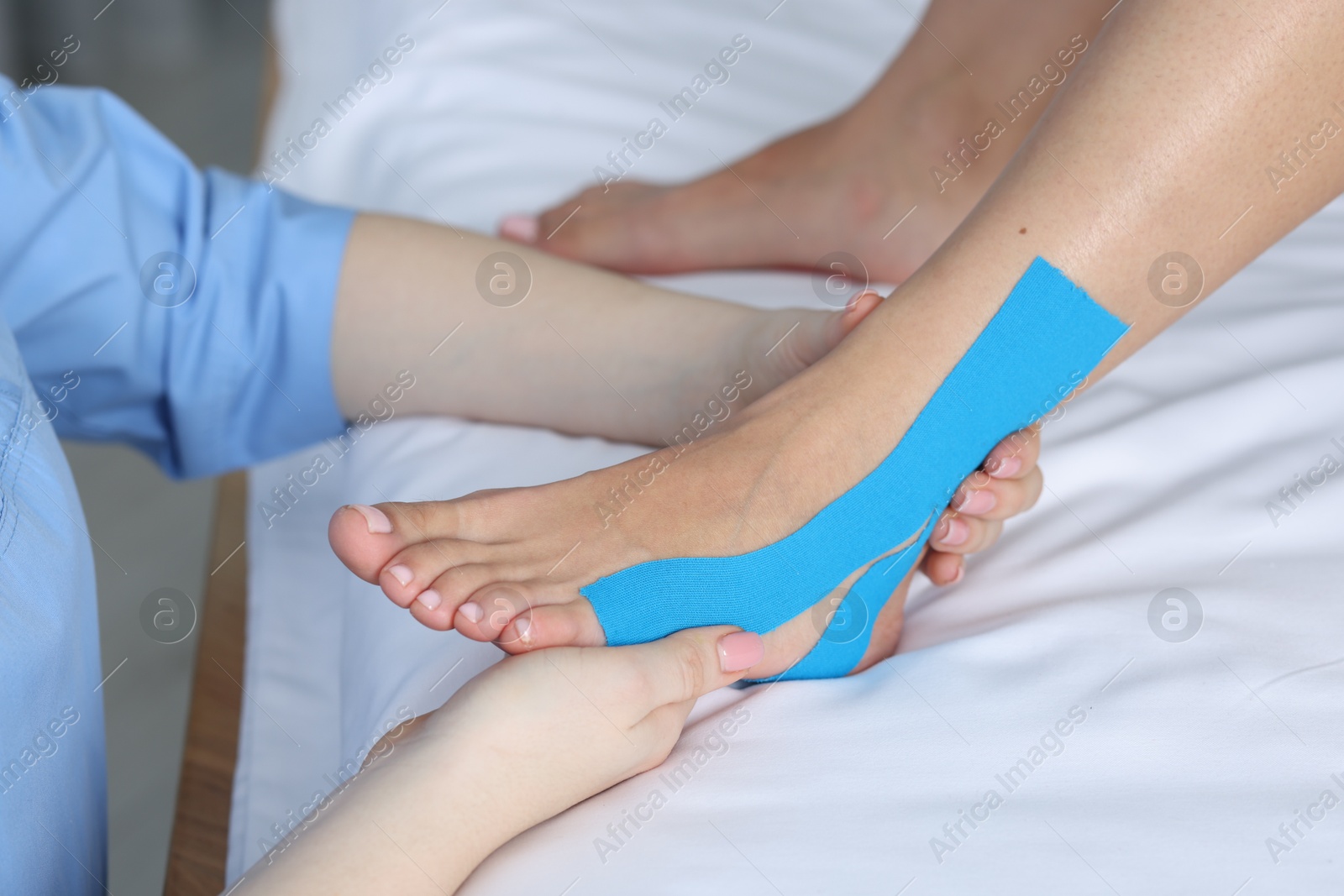 Photo of Doctor applying kinesio tapes to patient's foot in hospital, closeup