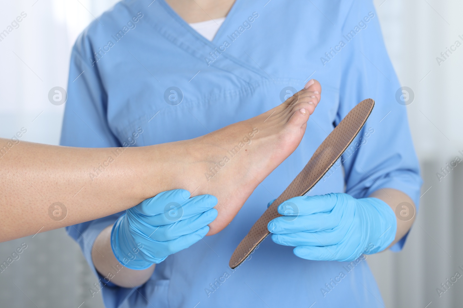 Photo of Doctor fitting insole to patient's foot in hospital, closeup