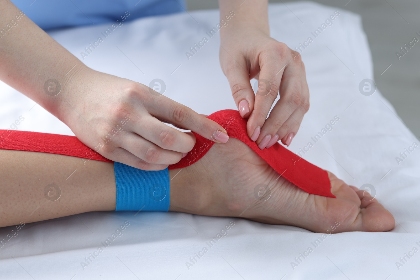 Photo of Doctor applying kinesio tapes to patient's foot in hospital, closeup