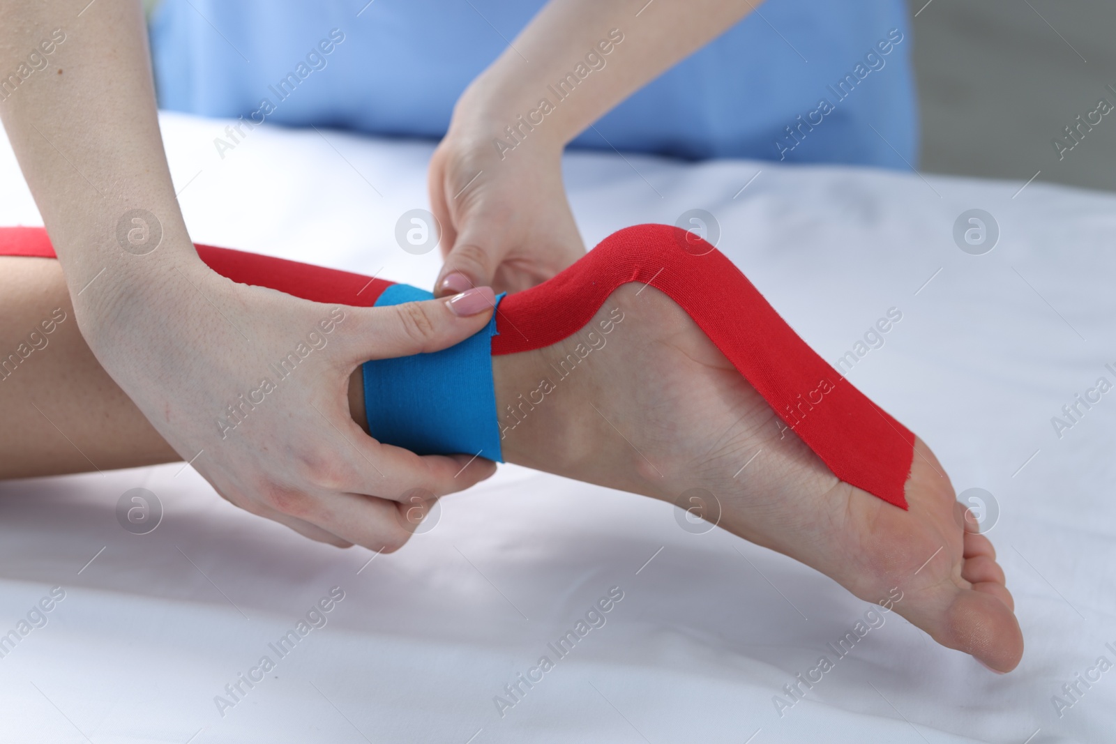 Photo of Doctor applying kinesio tapes to patient's foot in hospital, closeup