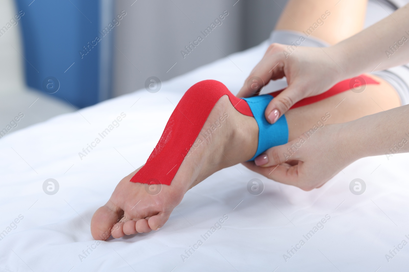 Photo of Doctor applying kinesio tapes to patient's foot in hospital, closeup