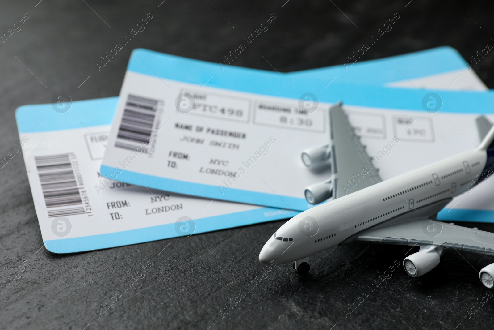 Photo of Travel agency. Flight tickets and plane model on dark textured table, closeup