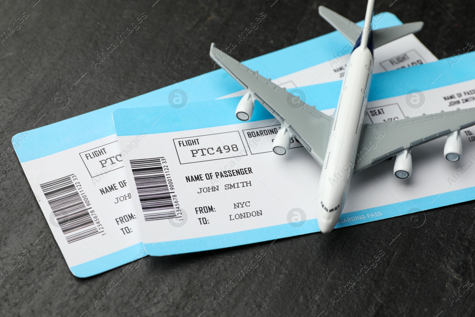 Photo of Travel agency. Flight tickets and plane model on dark textured table, closeup