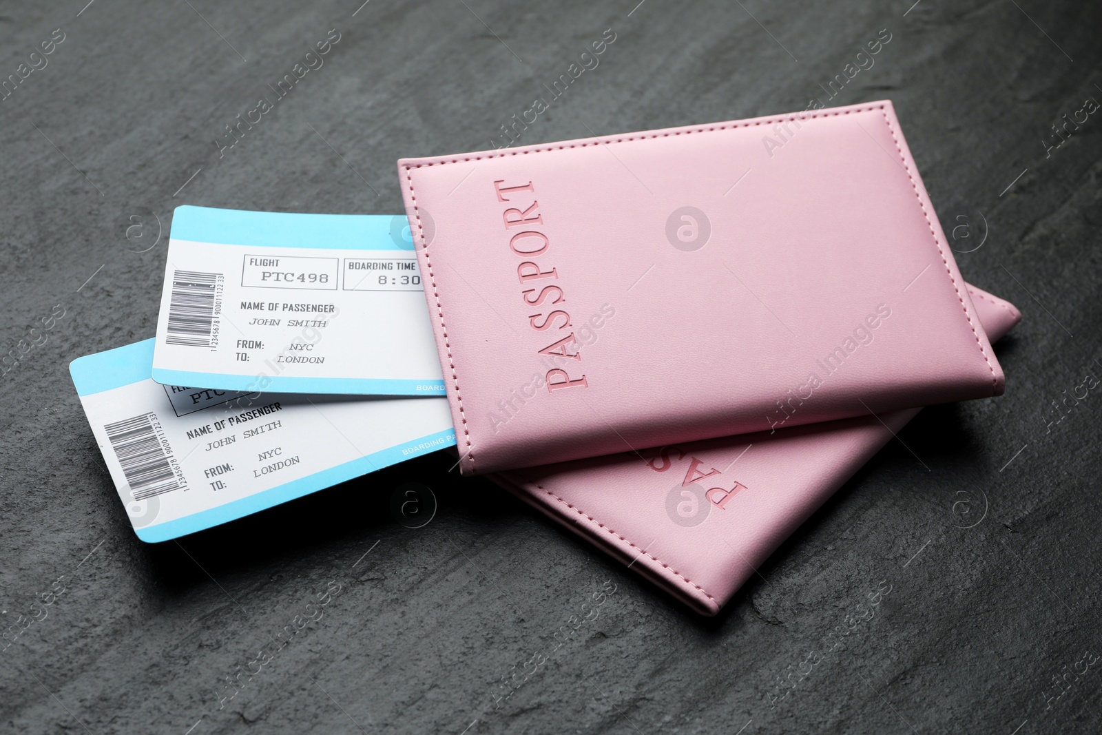 Photo of Travel agency. Flight tickets and passports on dark textured table, closeup