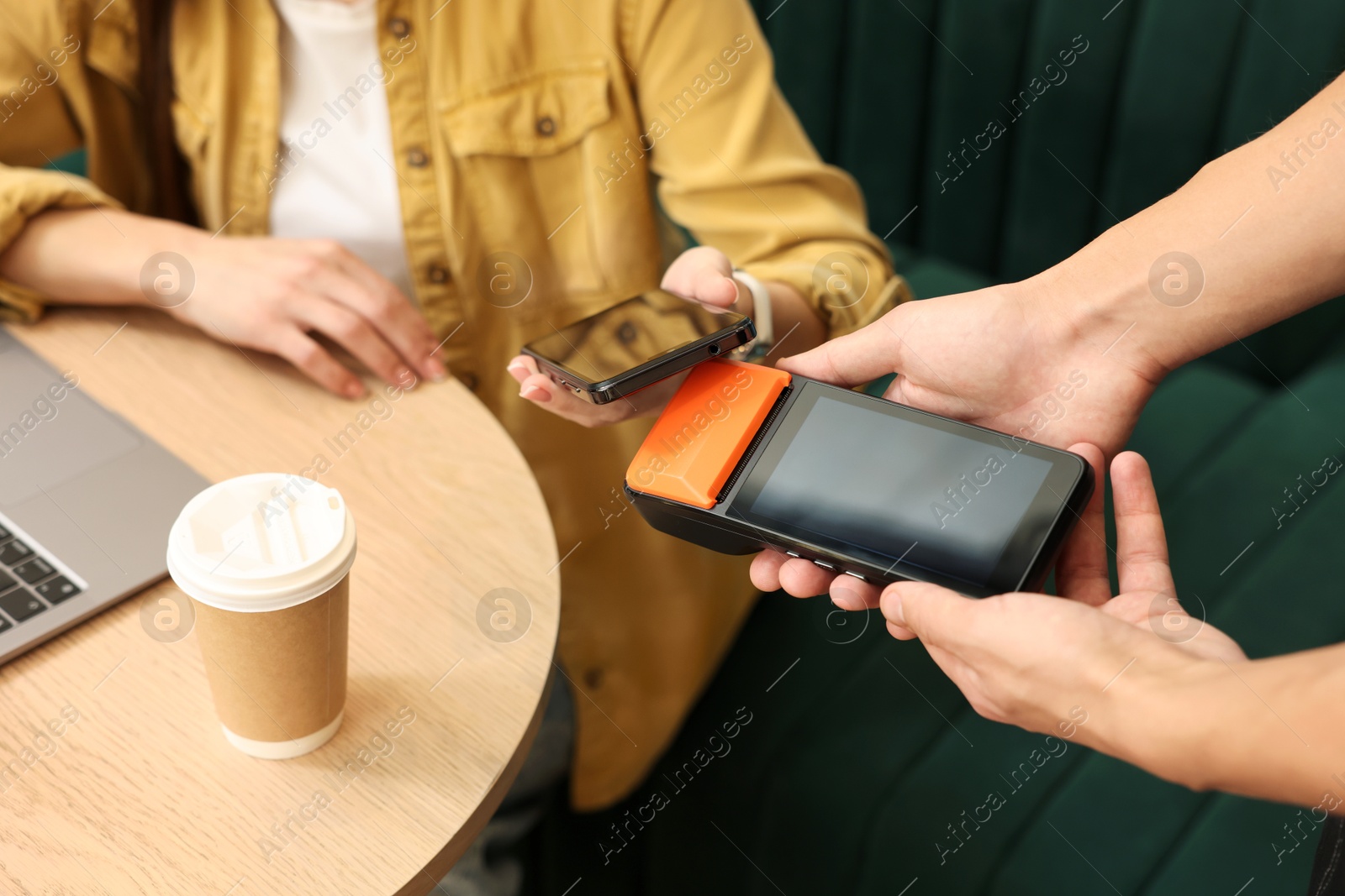 Photo of Woman paying with smartphone via terminal in cafe, closeup