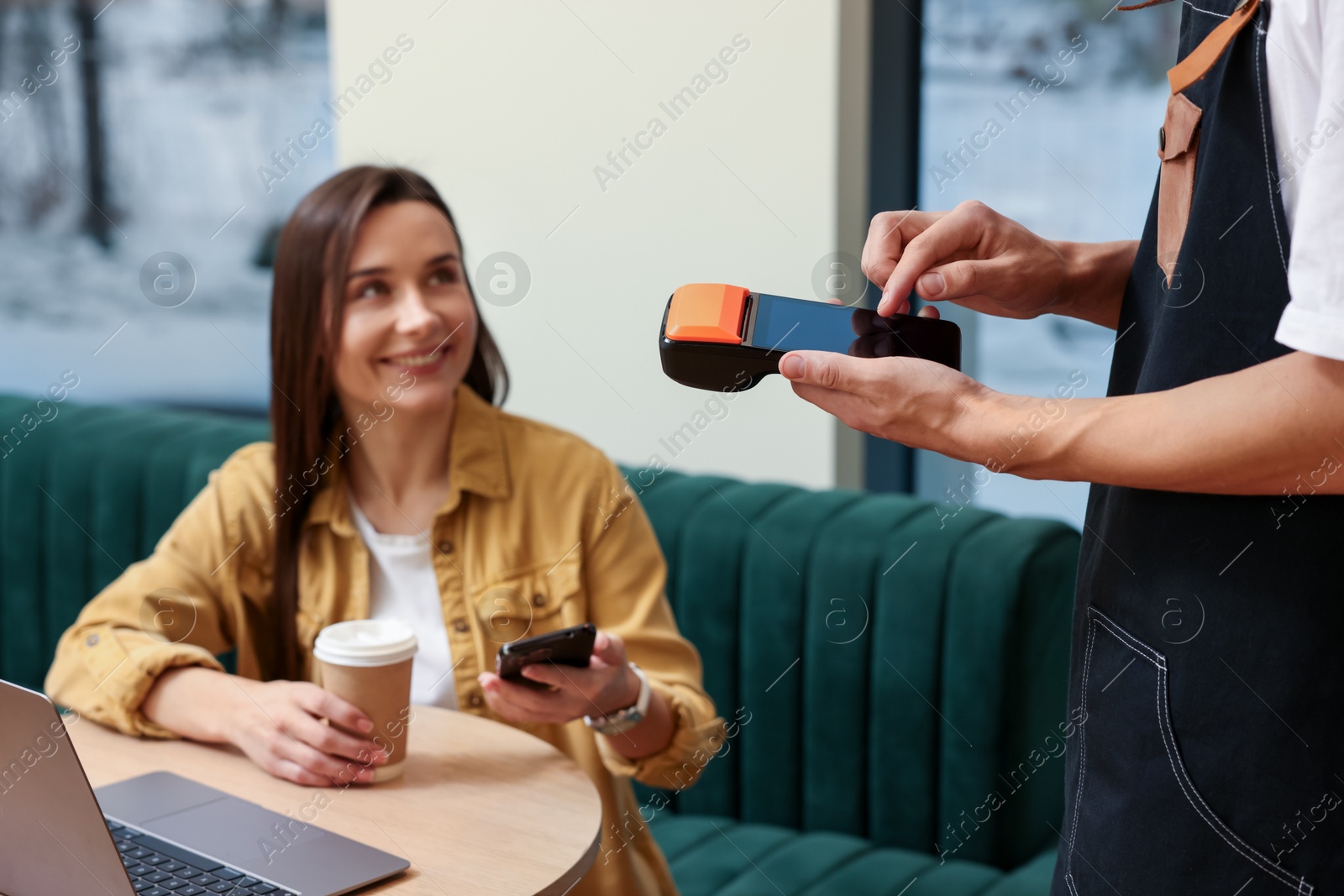 Photo of Waiter taking payment from client via terminal in cafe, selective focus