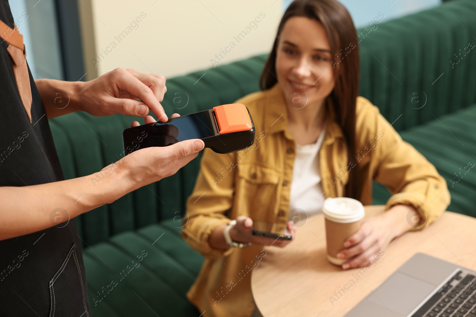 Photo of Waiter taking payment from client via terminal in cafe, selective focus