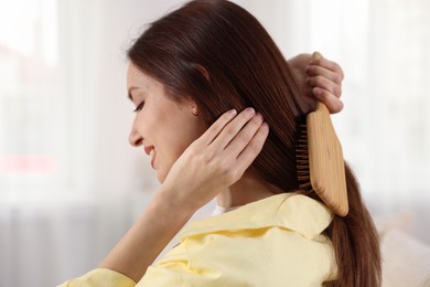 Photo of Woman brushing her beautiful hair at home