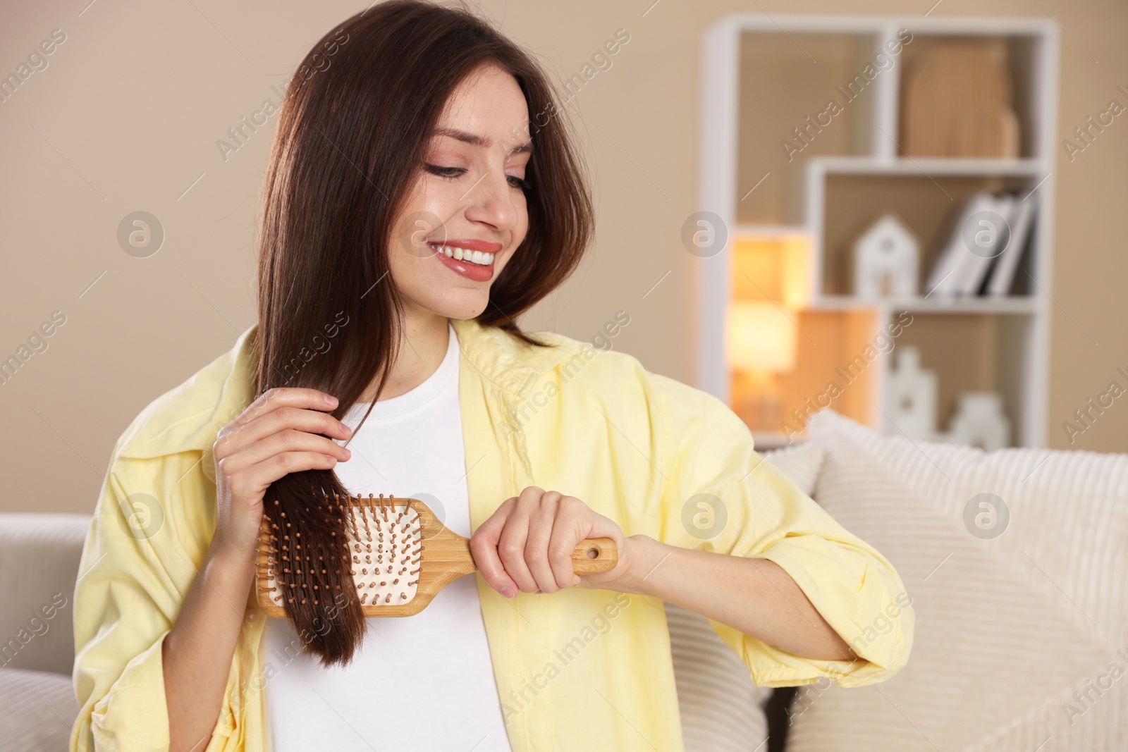 Photo of Smiling woman brushing her hair at home