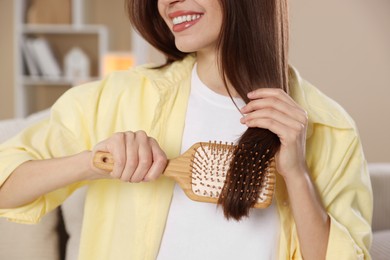 Photo of Woman brushing her hair at home, closeup