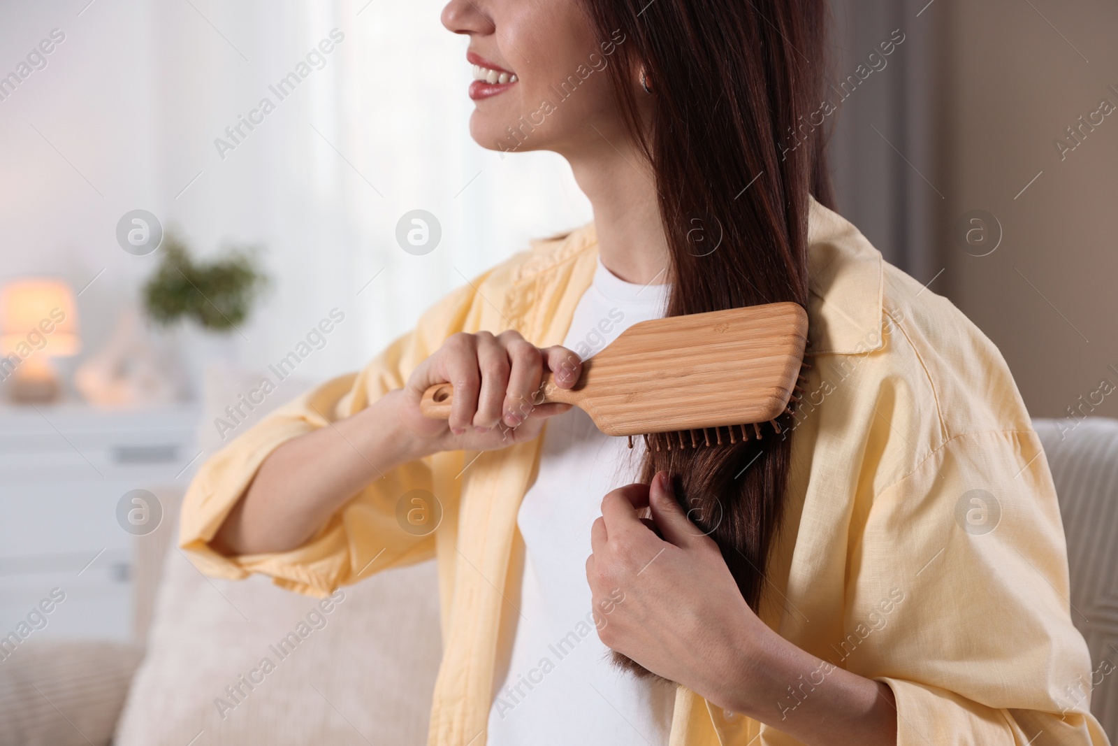 Photo of Woman brushing her hair at home, closeup