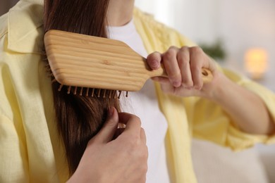 Photo of Woman brushing her hair at home, closeup