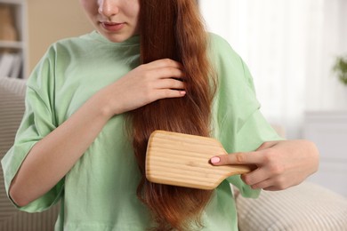 Photo of Teenage girl brushing her hair at home, closeup