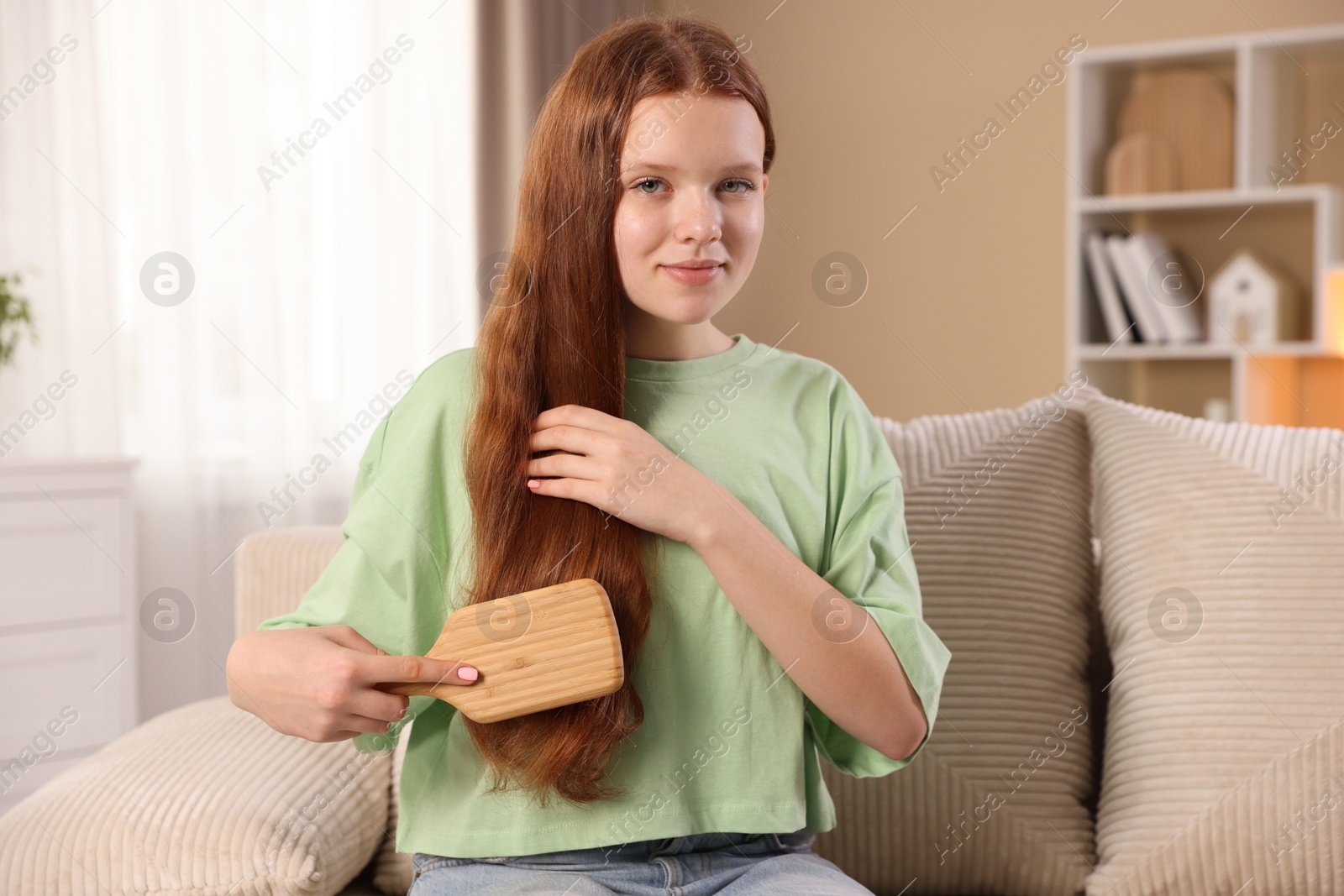 Photo of Beautiful teenage girl brushing her hair at home