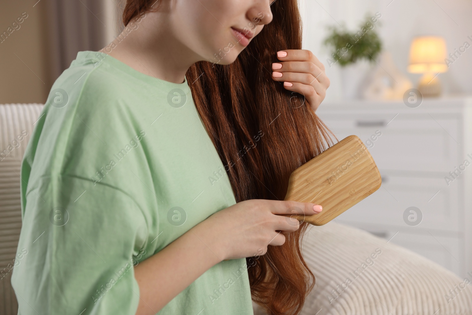 Photo of Teenage girl brushing her hair at home, closeup