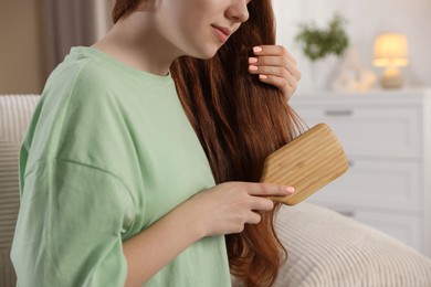 Photo of Teenage girl brushing her hair at home, closeup