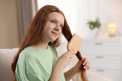 Photo of Beautiful teenage girl brushing her hair at home