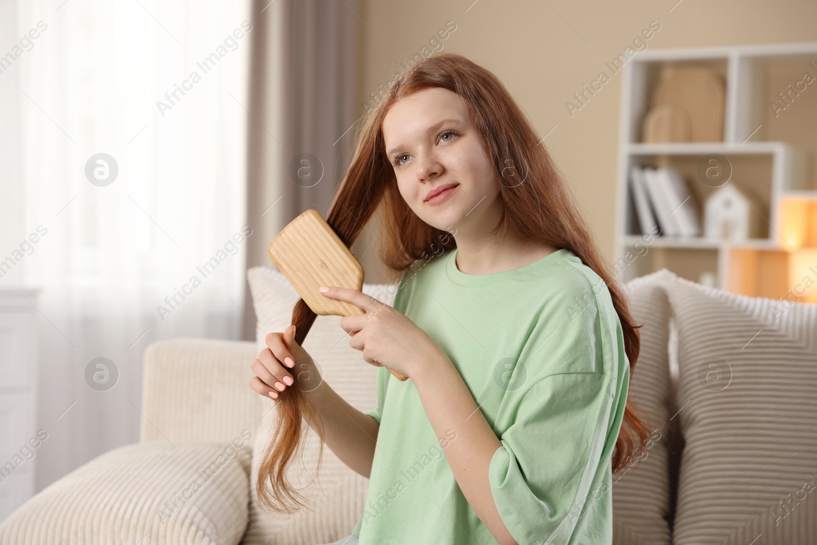 Photo of Beautiful teenage girl brushing her hair at home