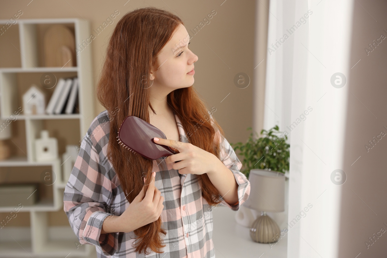 Photo of Beautiful teenage girl brushing her hair at home