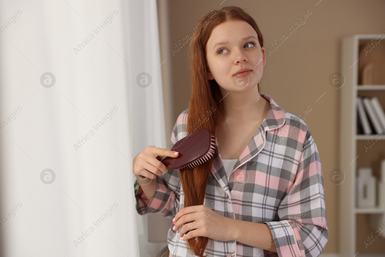 Photo of Beautiful teenage girl brushing her hair at home