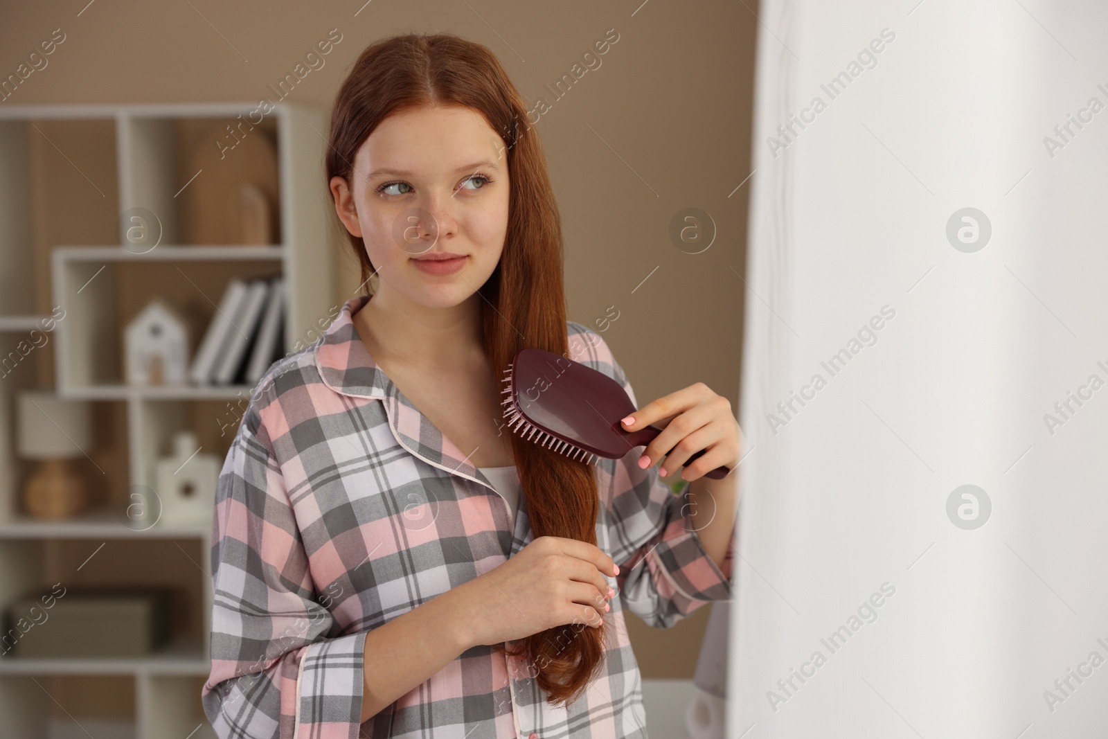 Photo of Beautiful teenage girl brushing her hair at home