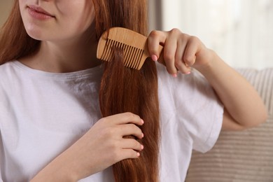 Photo of Teenage girl brushing her hair with comb at home, closeup