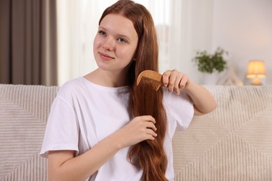 Photo of Beautiful teenage girl brushing her hair with comb at home