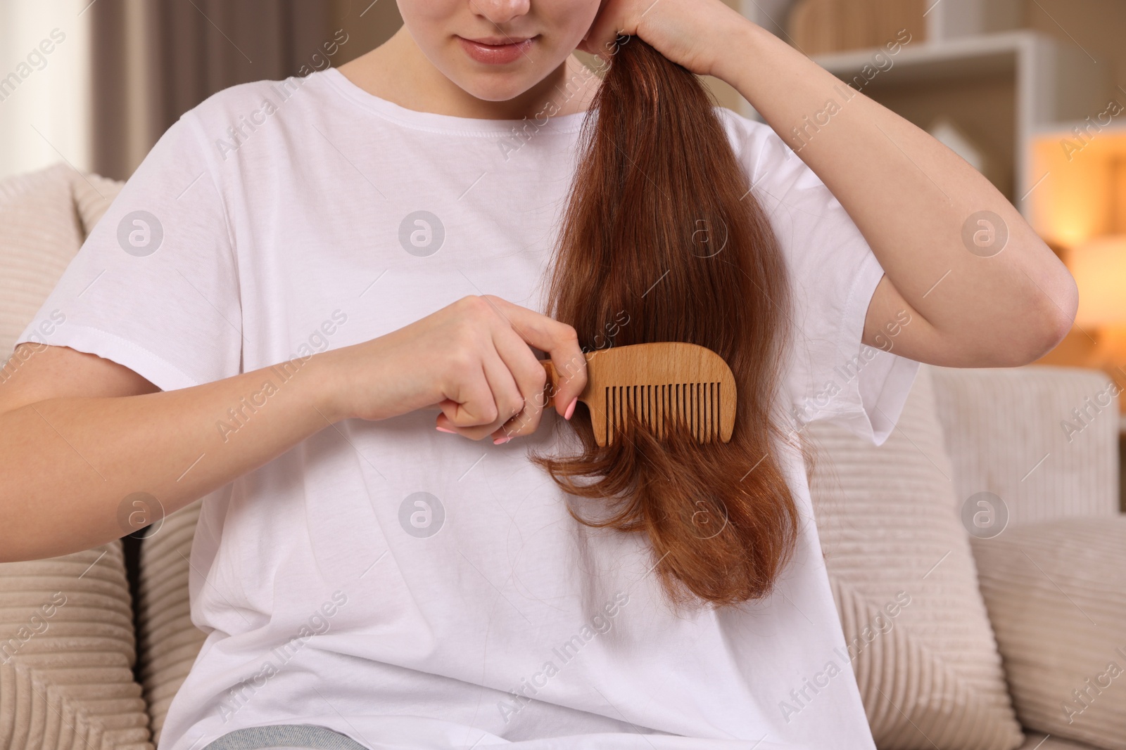 Photo of Teenage girl brushing her hair with comb at home, closeup