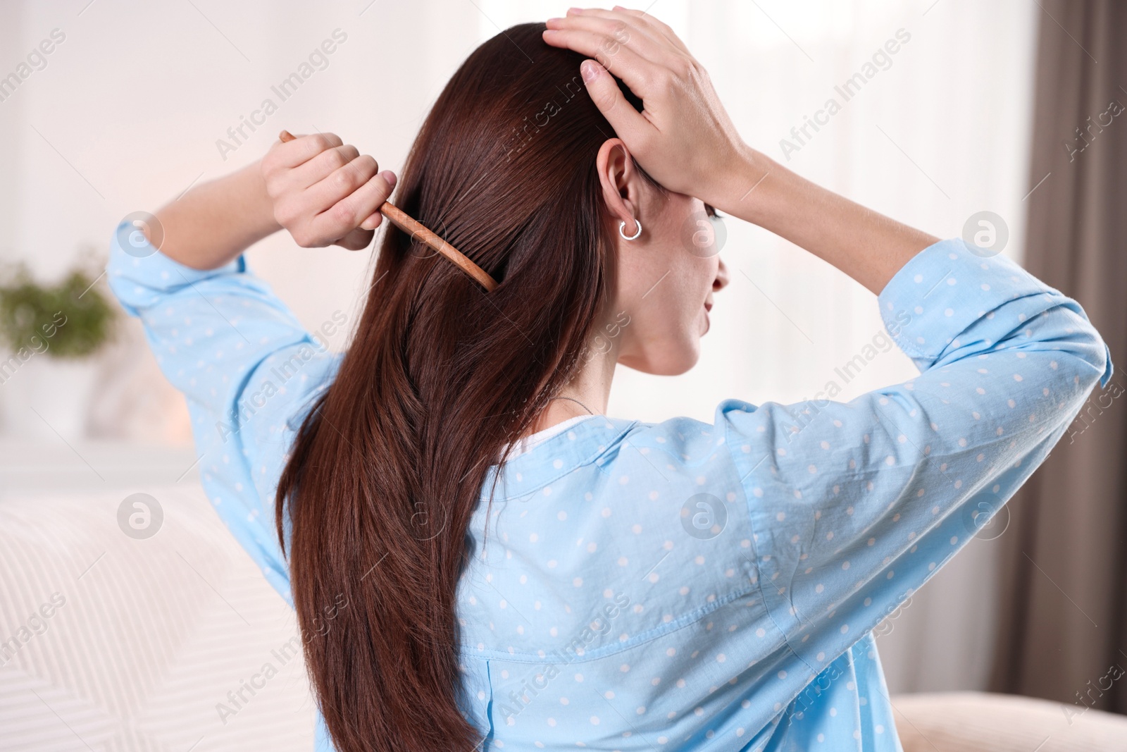 Photo of Woman brushing her hair with comb at home