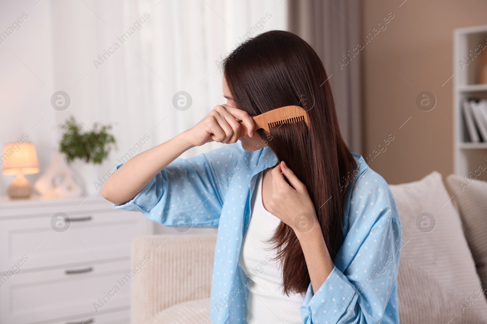 Photo of Woman brushing her hair with comb at home