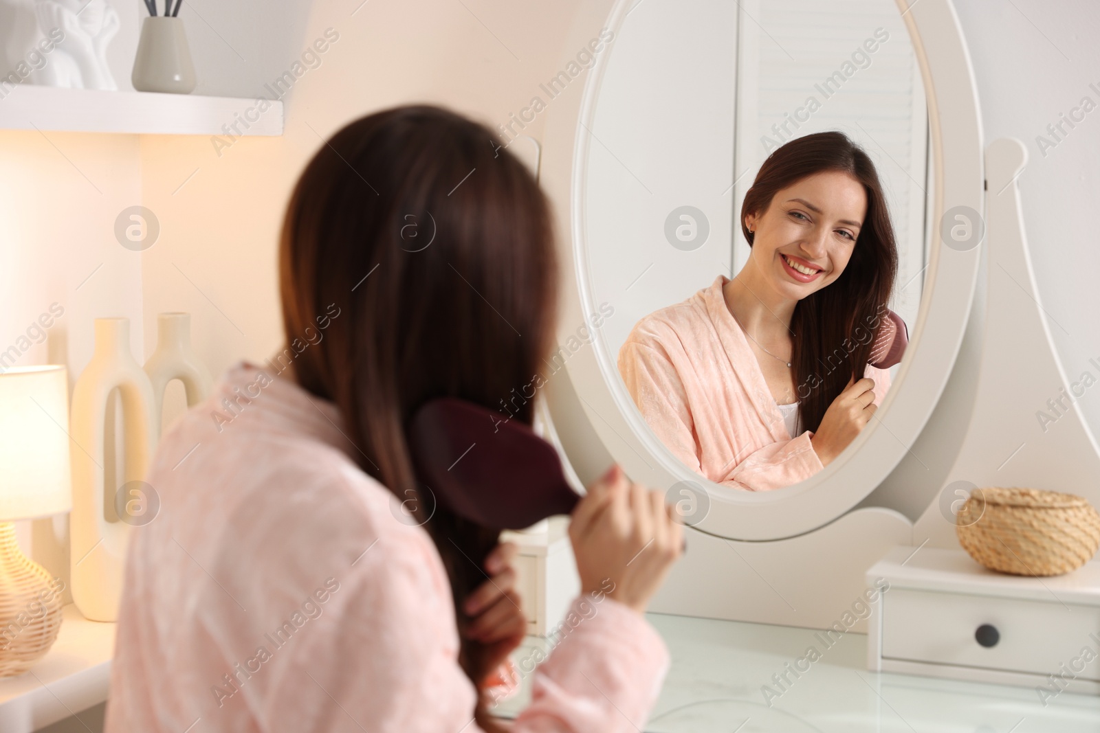 Photo of Beautiful woman brushing her hair near mirror at home, selective focus