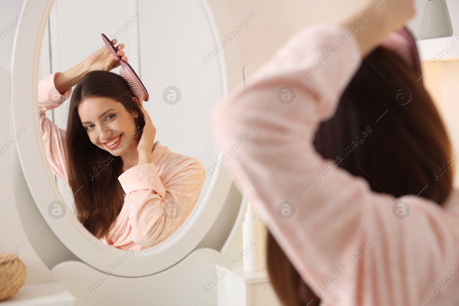 Photo of Beautiful woman brushing her hair near mirror at home, selective focus