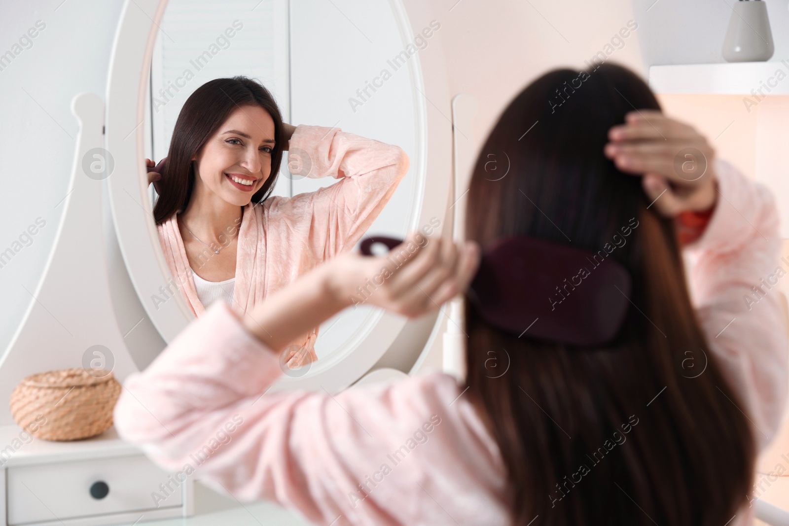 Photo of Beautiful woman brushing her hair near mirror at home, selective focus