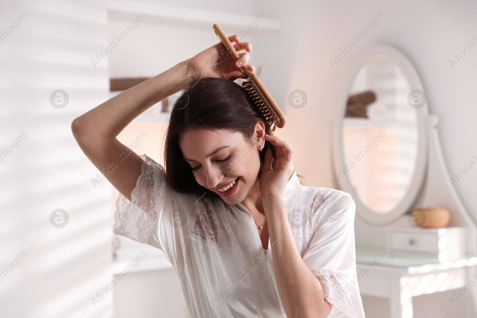 Photo of Smiling woman brushing her hair at home