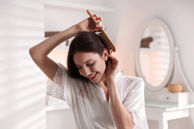 Photo of Smiling woman brushing her hair at home