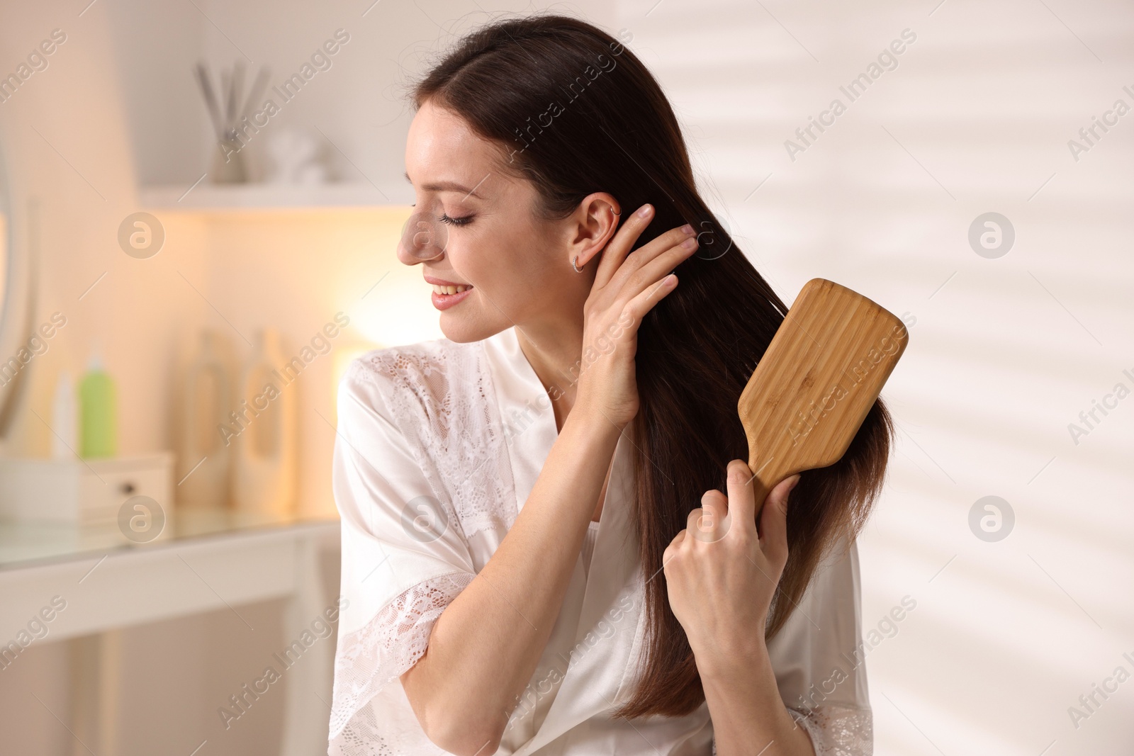 Photo of Smiling woman brushing her hair at home