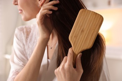 Photo of Woman brushing her hair at home, closeup