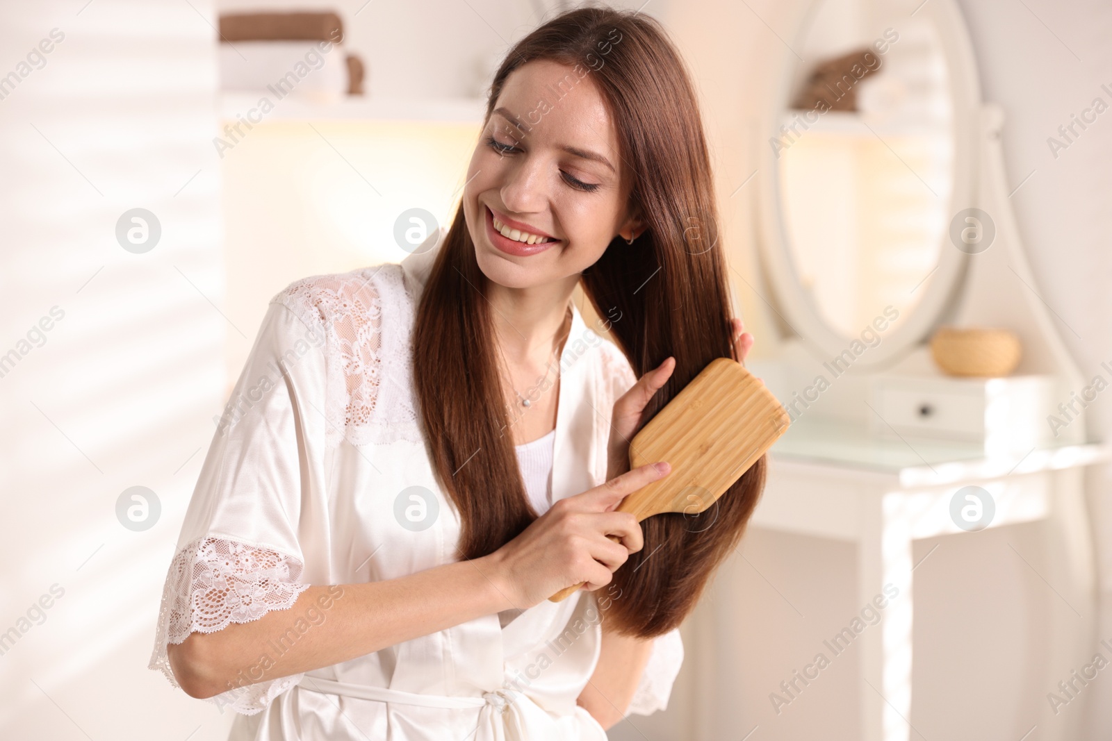 Photo of Smiling woman brushing her hair at home