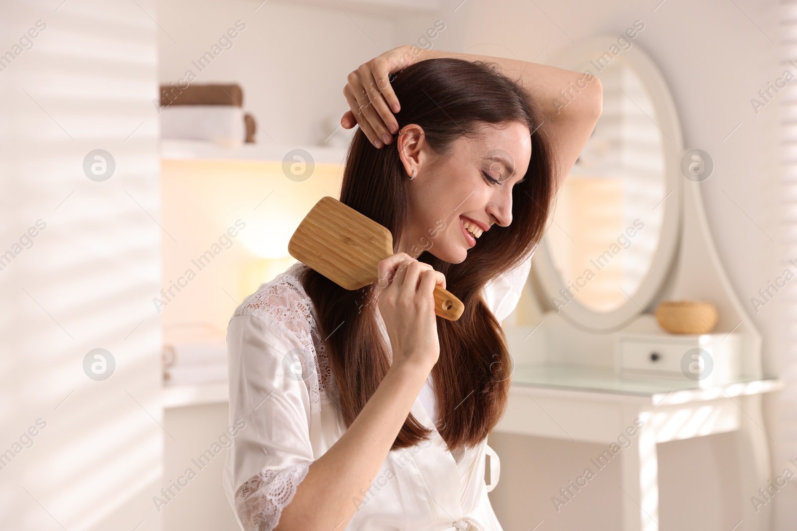 Photo of Smiling woman brushing her hair at home