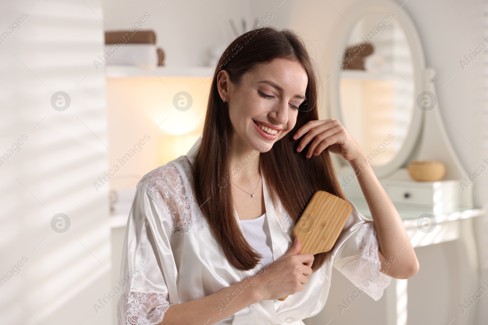 Photo of Smiling woman brushing her hair at home