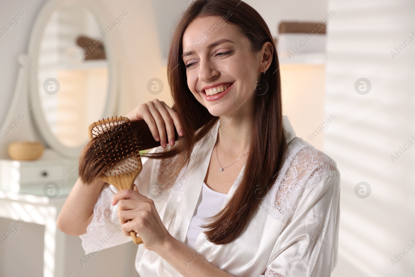 Photo of Smiling woman brushing her hair at home