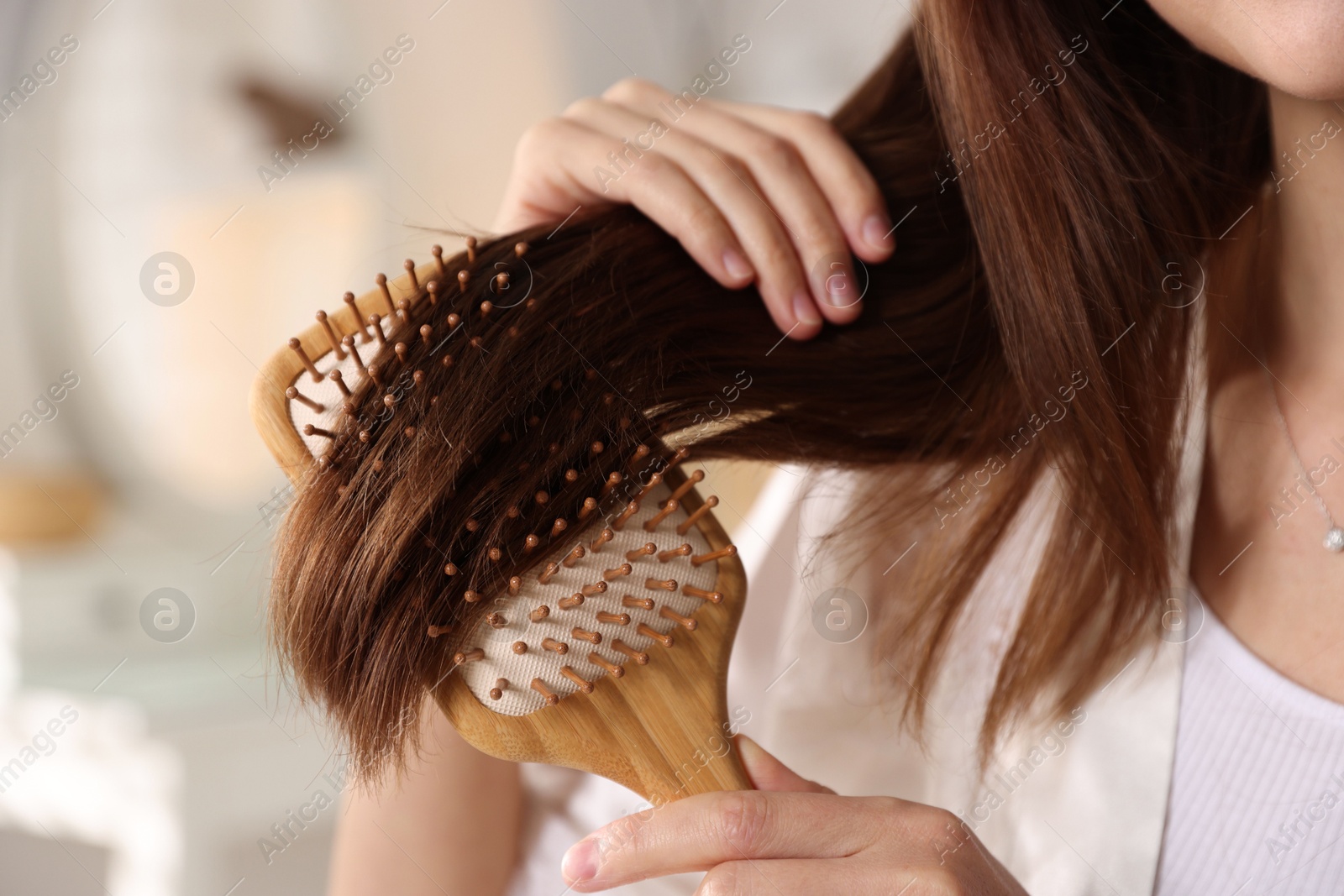 Photo of Woman brushing her hair at home, closeup