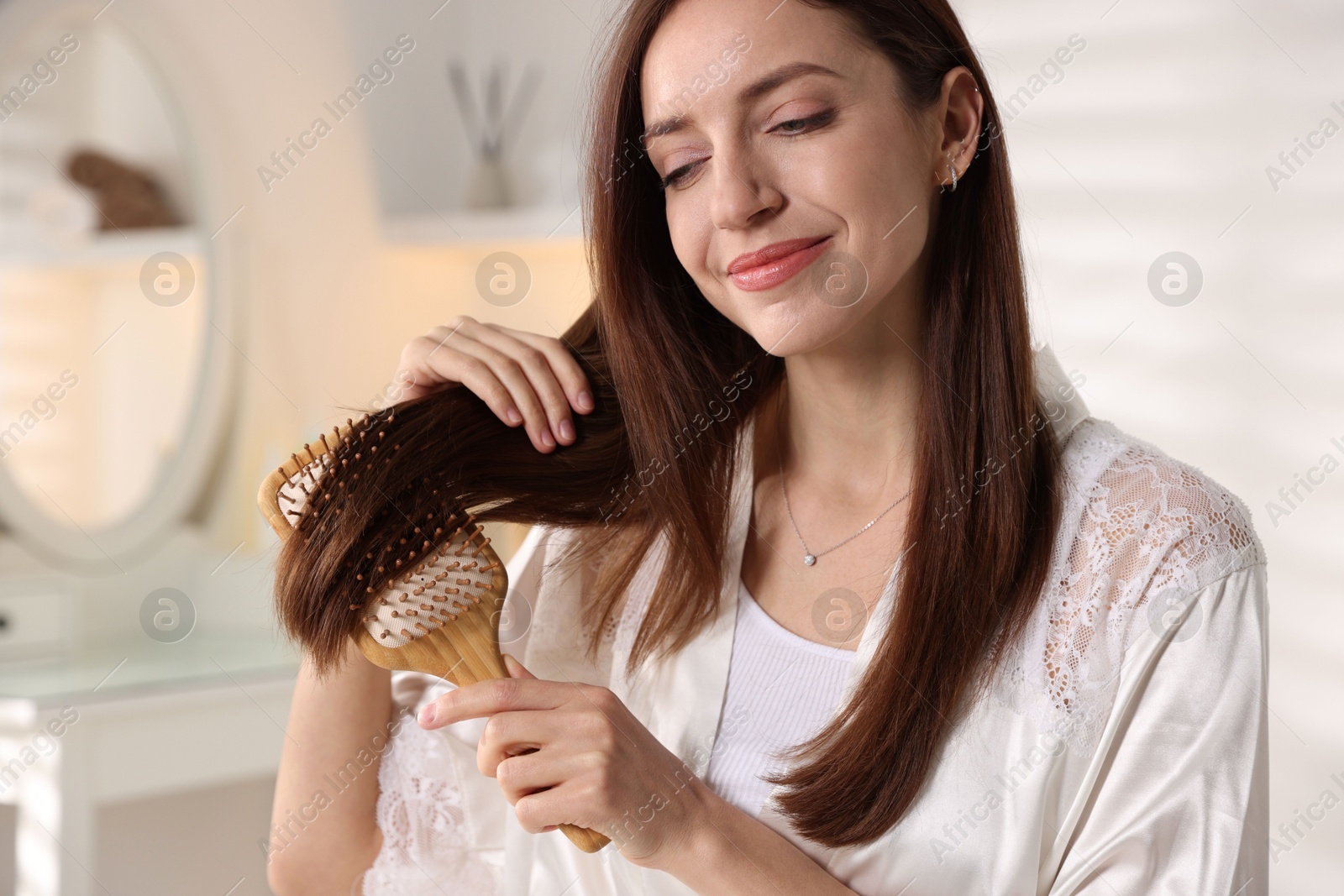 Photo of Beautiful woman brushing her hair at home