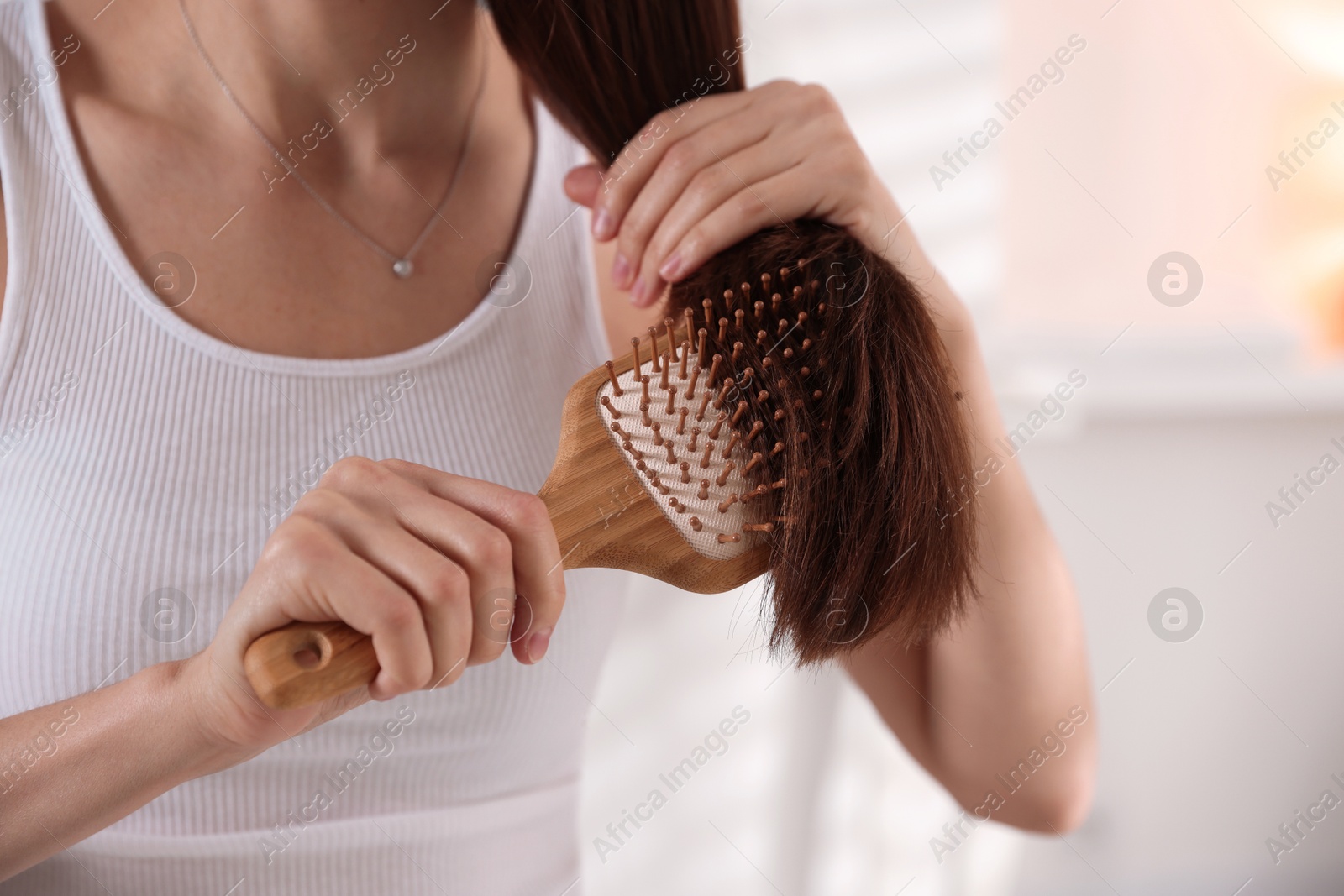 Photo of Woman brushing her beautiful hair indoors, closeup