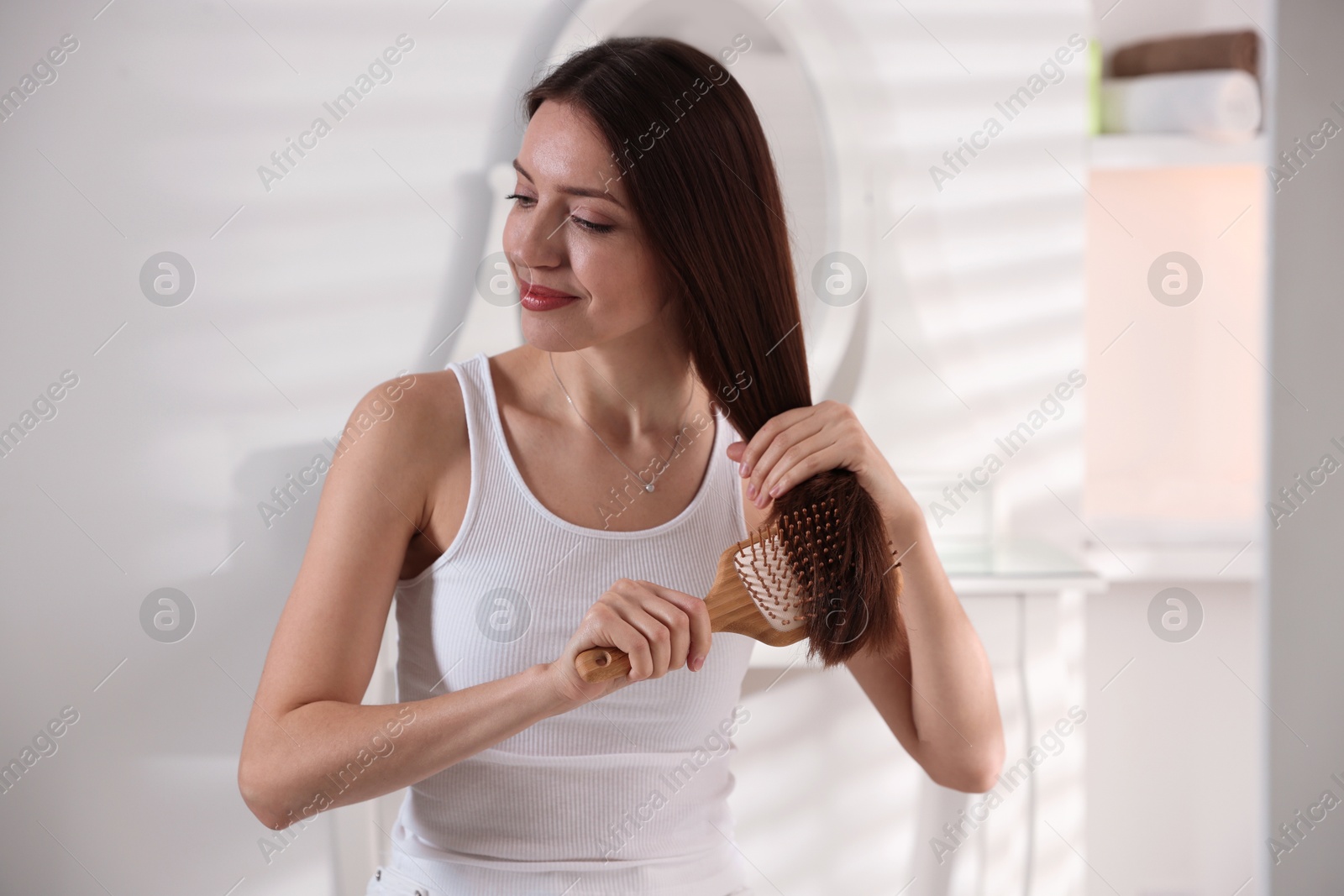 Photo of Beautiful woman brushing her hair at home