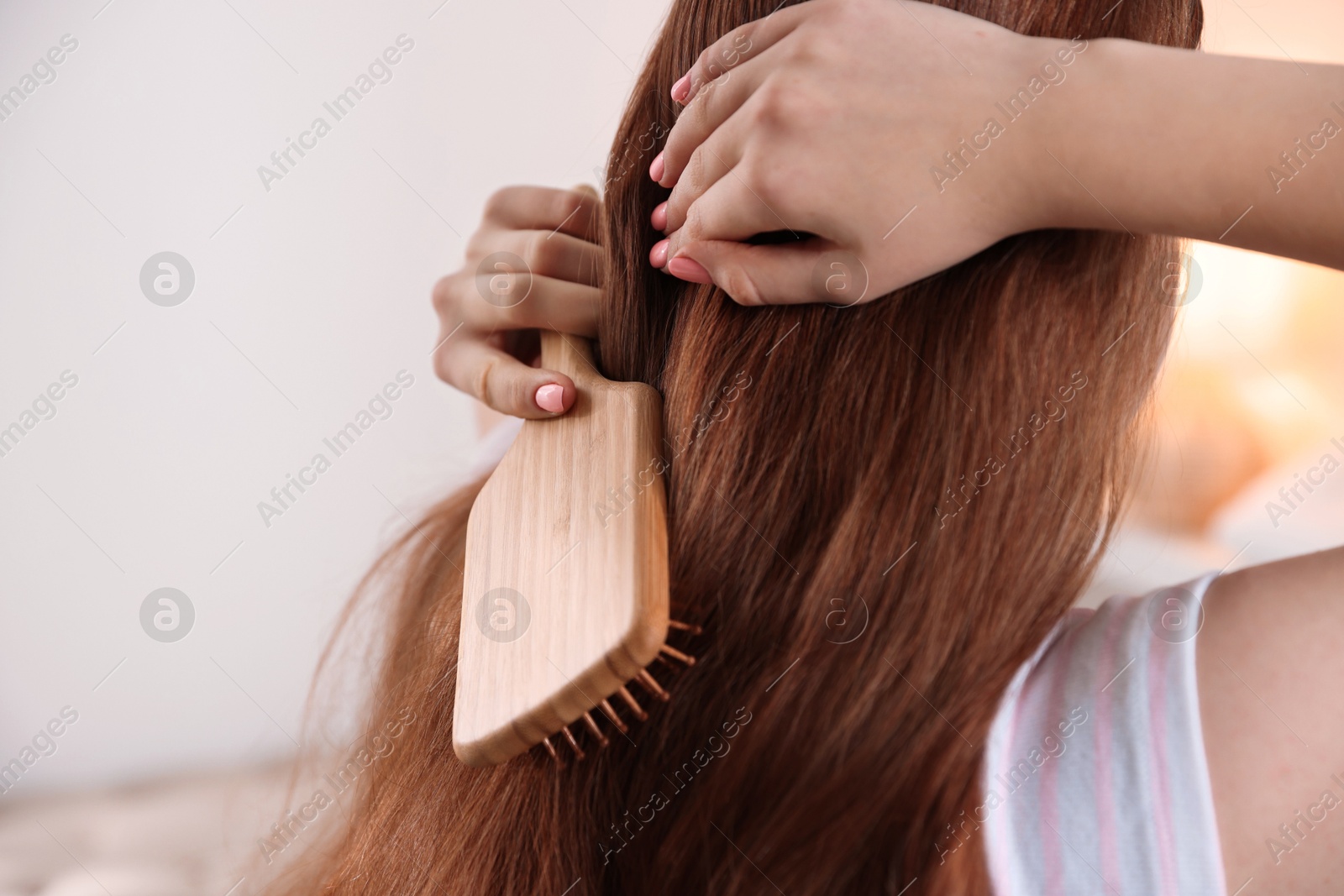 Photo of Teenage girl brushing her hair indoors, closeup