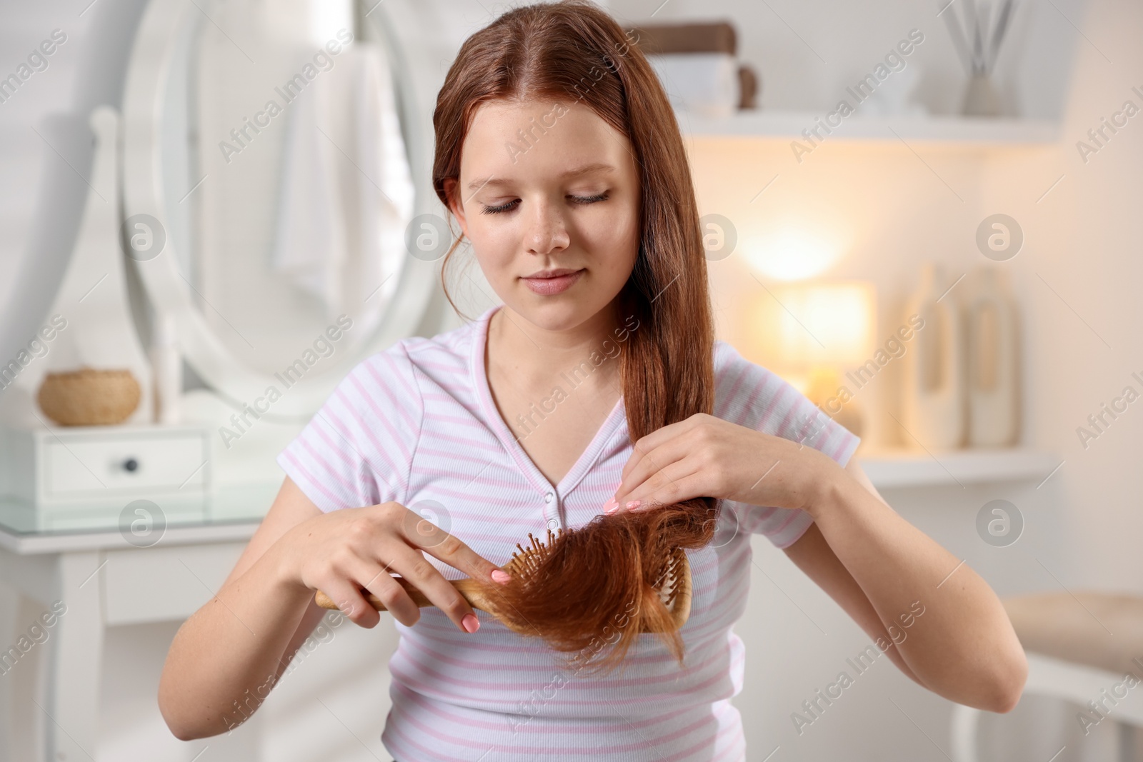 Photo of Beautiful teenage girl brushing her hair at home