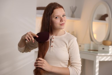 Photo of Beautiful teenage girl brushing her hair at home