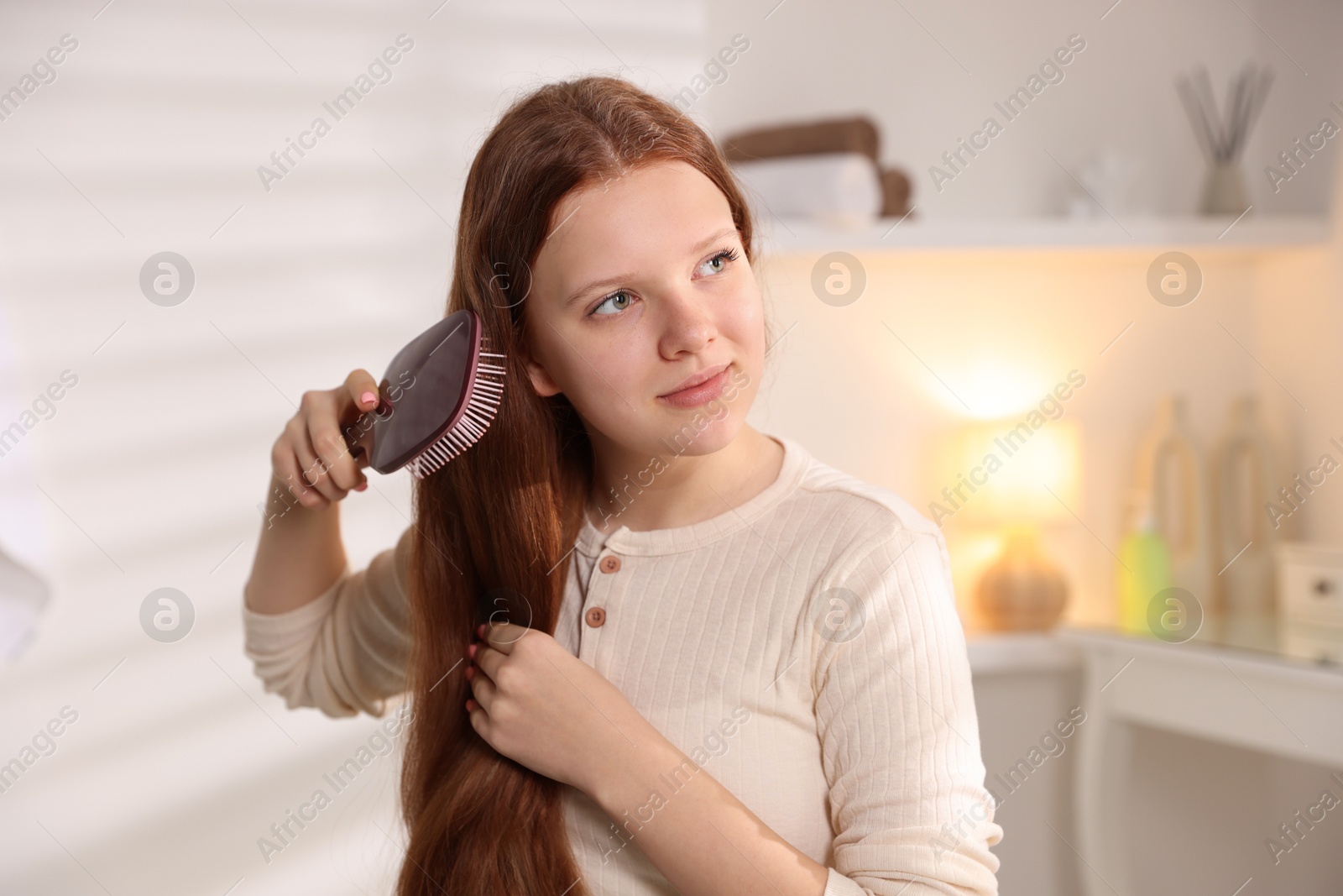 Photo of Beautiful teenage girl brushing her hair at home