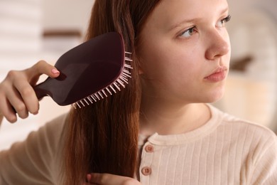 Photo of Beautiful teenage girl brushing her hair at home, closeup